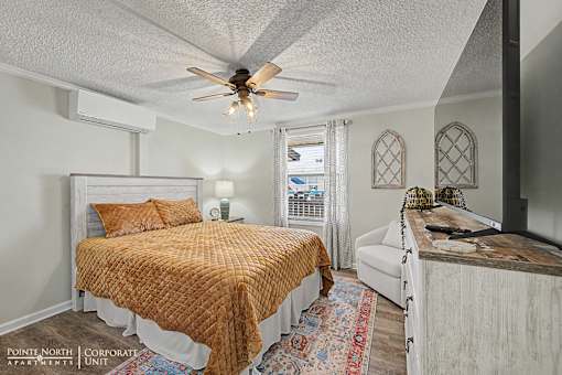 A bedroom with a bed, a couch, and a ceiling fan.