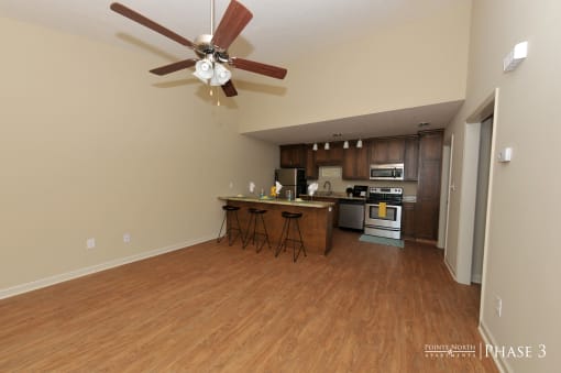 an open kitchen and living room with wooden floors and a ceiling fan