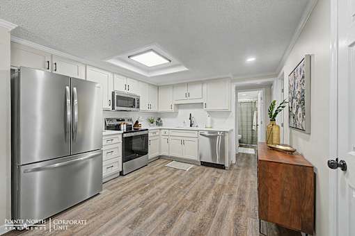 A kitchen with a refrigerator, microwave, oven, and cabinets.