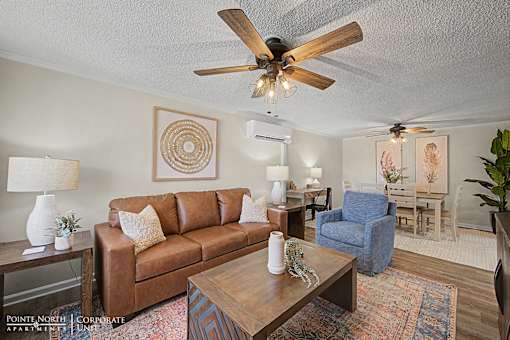 A living room with a brown couch, a blue chair, and a ceiling fan.