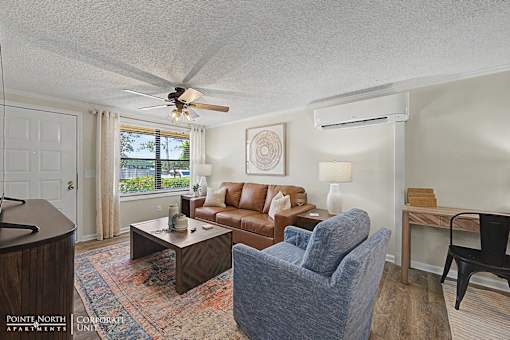 A living room with a brown couch, a blue chair, and a ceiling fan.
