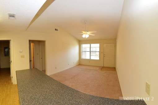 the living room of an empty house with a ceiling fan