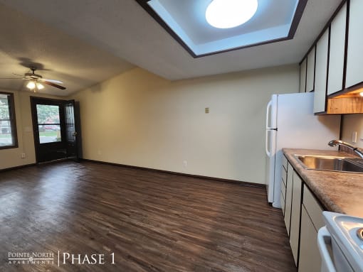a kitchen and living room with a refrigerator and a sink