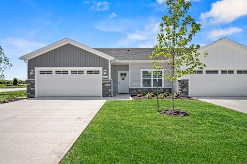 A house with a grey garage door and a tree in front.