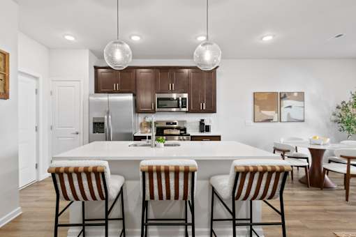 A modern kitchen with a white island and striped barstools.
