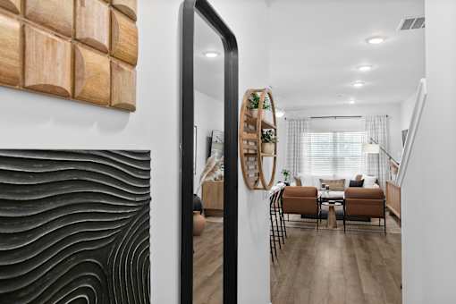 A modern living room with a wooden wall art and a mirror reflecting the room.