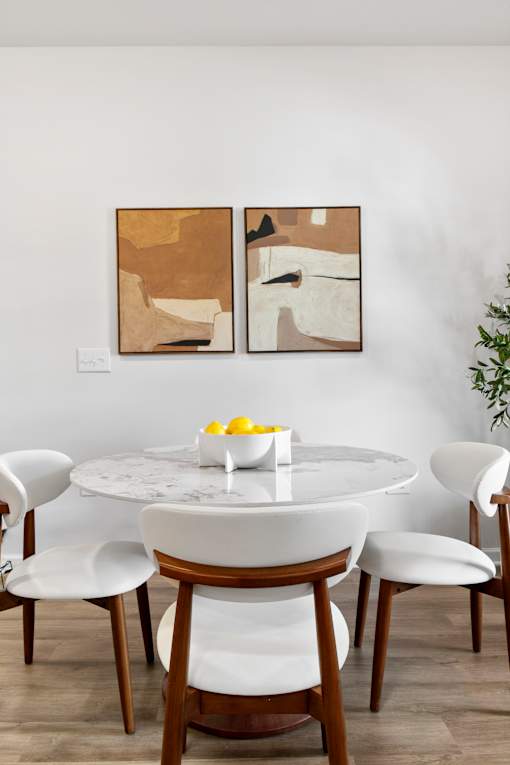 A dining table with chairs and a bowl of lemons on it.