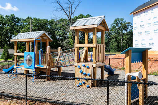 A playground with a wooden swing set and a blue slide.
