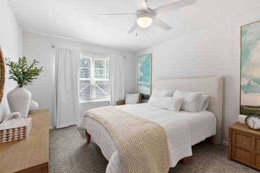 A bedroom with a large bed and a ceiling fan.