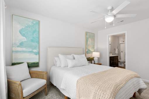 A bedroom with a bed, chair, and painting on the wall.