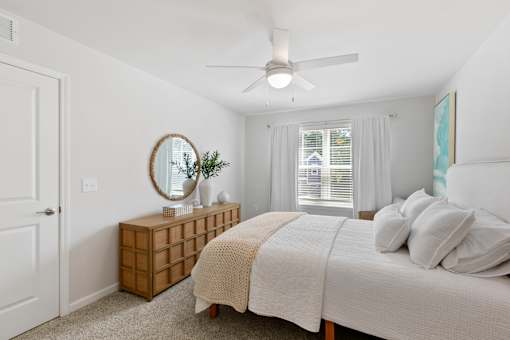 A bedroom with a bed, a dresser, and a window.