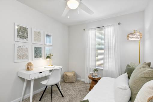 A white desk with a chair and a lamp on a table in a room.