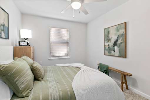 A bedroom with a bed, nightstand, and a painting on the wall.