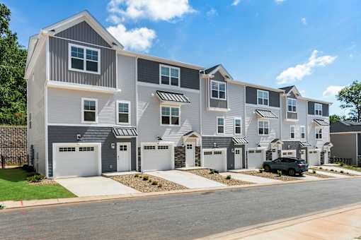 A row of modern townhouses with garages and driveways.