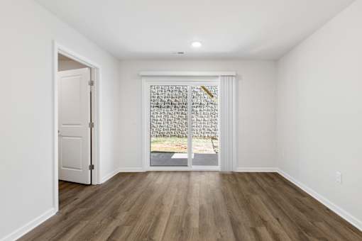 A room with a white door and a window with a view of a stone wall.