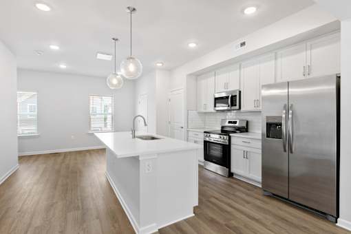 A modern kitchen with stainless steel appliances and wooden floors.
