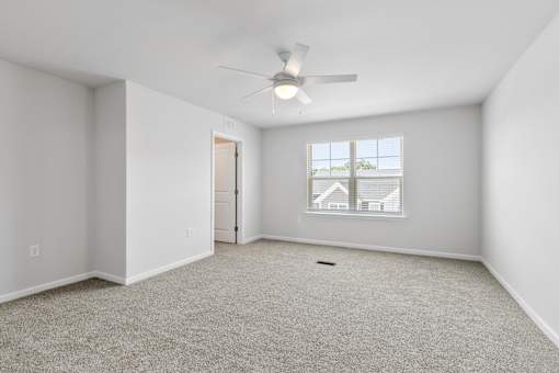 A room with a ceiling fan and a window with a view of a house.