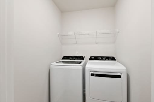 Two white front load washing machines in a laundry room.