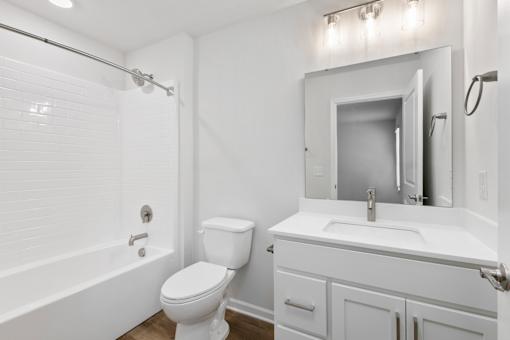 A white bathroom with a toilet, sink, and bathtub.