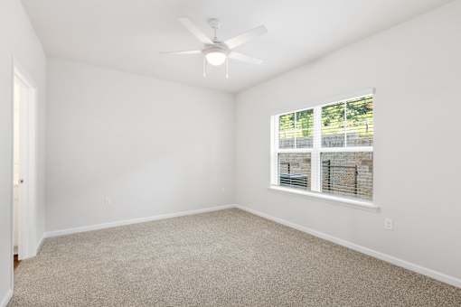 A room with a ceiling fan and a window with blinds.