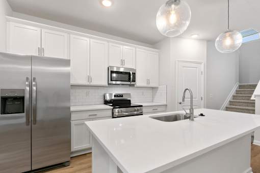 A modern kitchen with a white countertop and stainless steel appliances.
