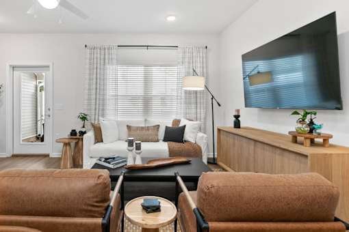 A living room with a white couch and brown chairs.