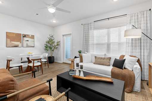 A living room with a brown couch, a black coffee table, and a white sofa.