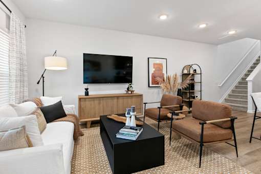 A living room with a white couch, a black coffee table, and a television.