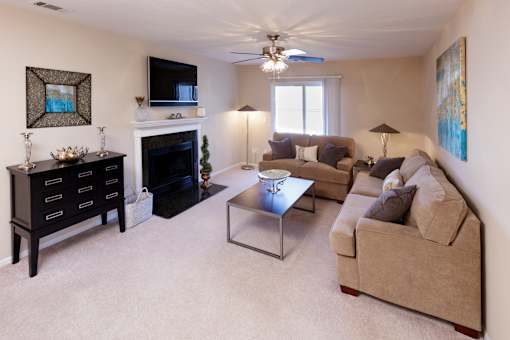 A living room with a fireplace, a couch, a coffee table, and a painting on the wall.