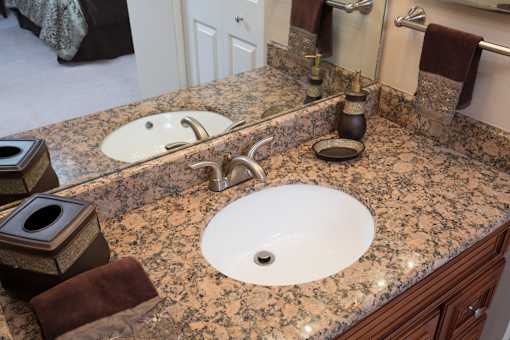 A bathroom with a granite countertop and a white sink.