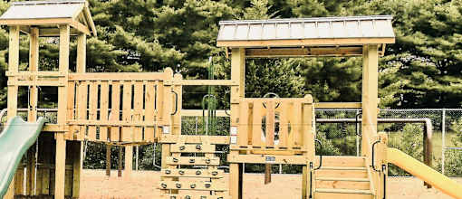 A wooden playground with a green slide and a yellow slide.