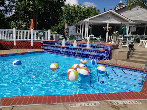 A pool with a white fence and a house in the background.