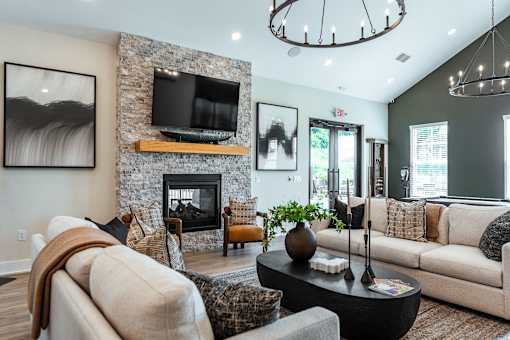 A living room with a stone fireplace and a television above it.