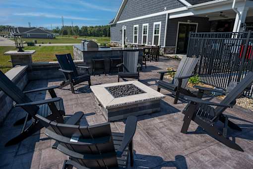 A patio with a fire pit and chairs.