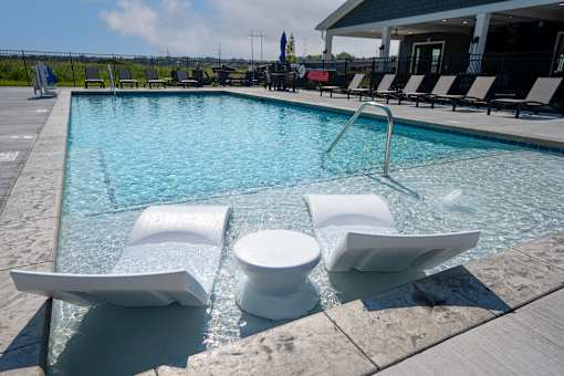 A pool with white chairs and a white toilet in the middle.