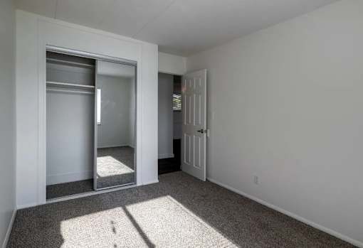 A room with a white door and a mirror on the wall.