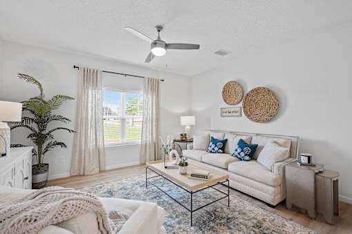 A living room with a white couch, a coffee table, and a ceiling fan.