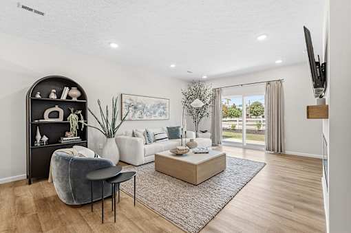 A living room with a grey chair, a black shelf, a white sofa, and a wooden coffee table.