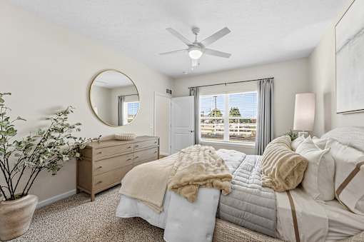 A bedroom with a large bed, a dresser, and a mirror.