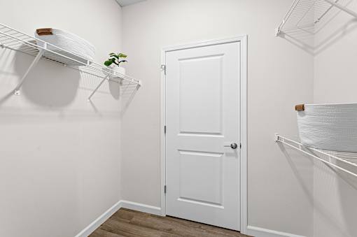 A white door is in the middle of a room with a shelf above it.