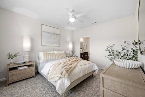 A bedroom with a bed, nightstands, and a ceiling fan.