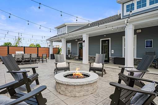 A patio with a fire pit and chairs.