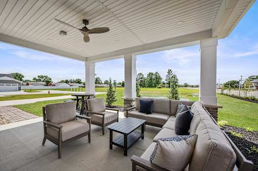 A patio with a couch, chairs, and a ceiling fan.