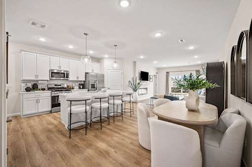 A modern kitchen with white cabinets and a dining table with chairs.