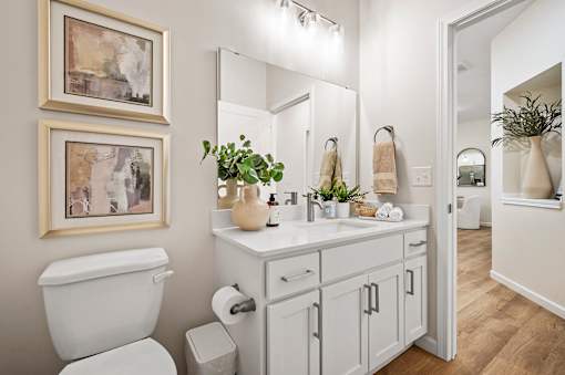 A white bathroom with a toilet, sink, and mirror.