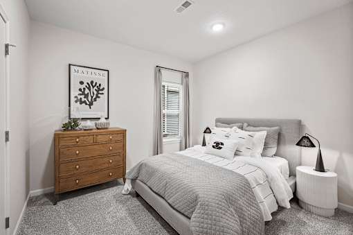 A bedroom with a bed, nightstand, and dresser.
