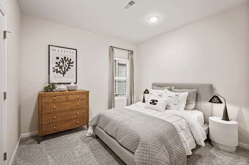 A bedroom with a bed, nightstand, and window.