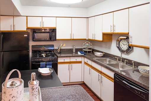 A kitchen with white cabinets and a black fridge.