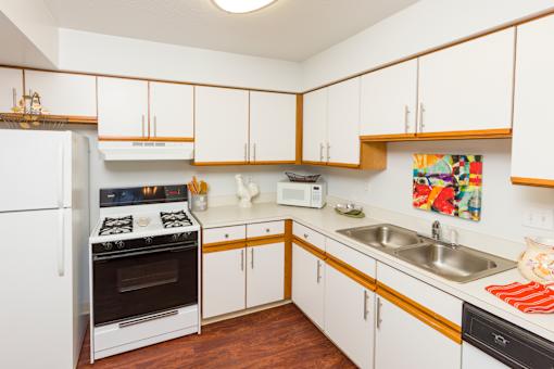 A kitchen with white cabinets and a white fridge.