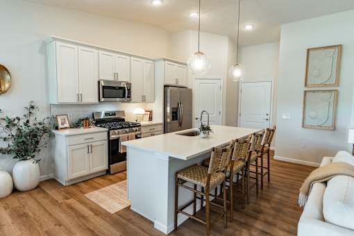 A kitchen with a white island and wooden chairs.